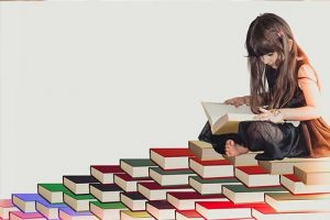 Girl sitting on top of a descending pile of books