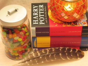 A candle laying on top of Harry potter books with a can of candy nex to the book