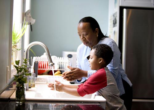 Mother teaching the good habit of washing hands before meals to her son