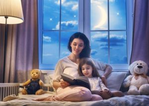 Mother and daughter reading a book on the bed
