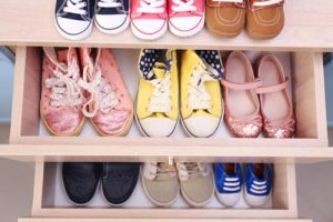 Different pairs of kids shoes places in a shoe rack.