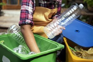 Hand digging into the recycled can and taking out plastic bottles