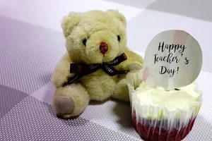 Teddy bear and cake with a note wishing Teacher's day