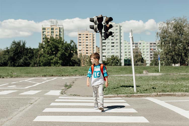 A young boy crossing the road on a zebra crossing.