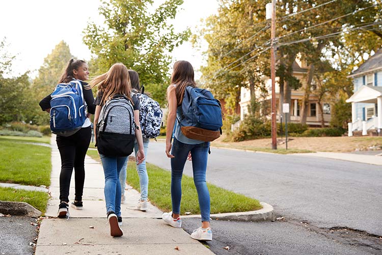 A group of girls walking on the pavement.