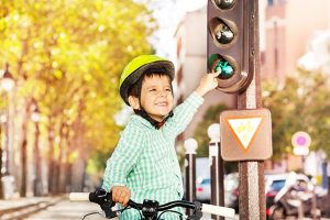 A young boy pointing at a traffic signal.