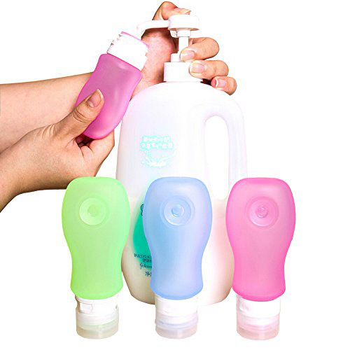 A hand transferring shampoo from a big container into small squeeze bottles with other colourful bottles lying around.