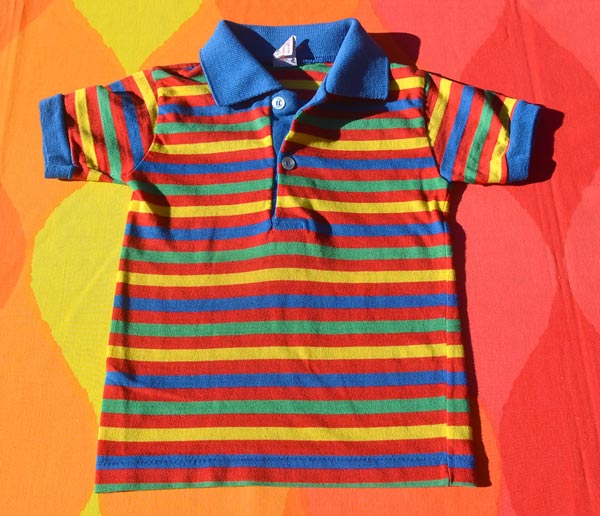 A colourful striped polo kids t-shirt laid on a colourful background