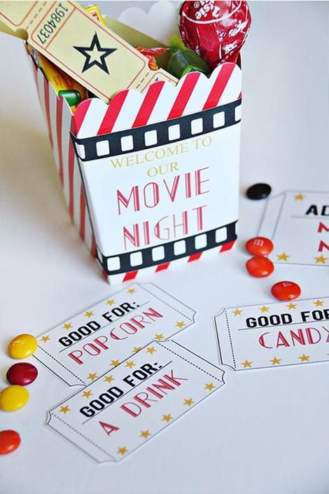 A Paper container filled with chocolates and ticket stubs with handmade movie tickets and M&M’S strewn around.