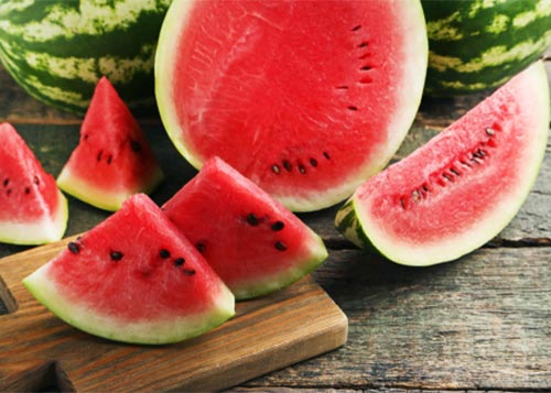 Watermelon slices placed on a wooden board.