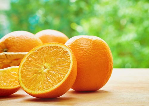 A couple of oranges on a wooden table.