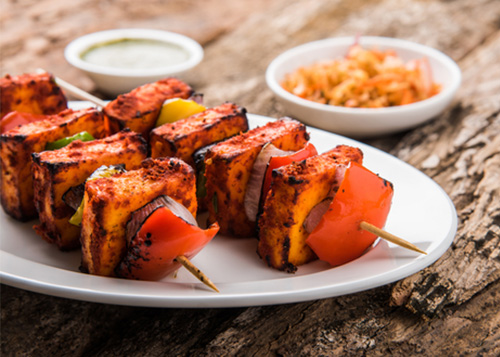 Paneer Tikka cubes skewed onto a wooden stick.