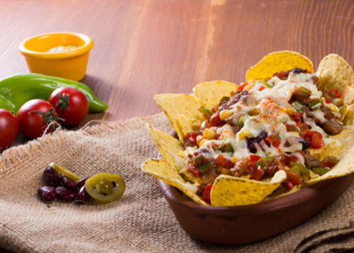 Nachos, cheese, and salsa served in a bowl.
