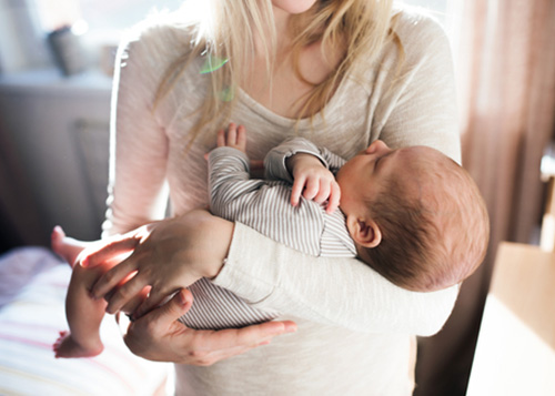 A mother swinging her baby back and forth in her arms.