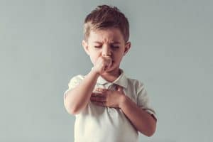 A young boy coughing.