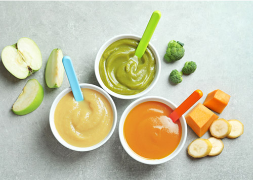 Three bowls of baby food placed along with the raw ingredients next to them.