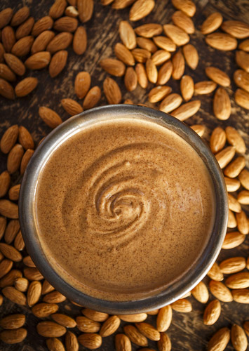 A bowl of almond butter surrounded by almonds