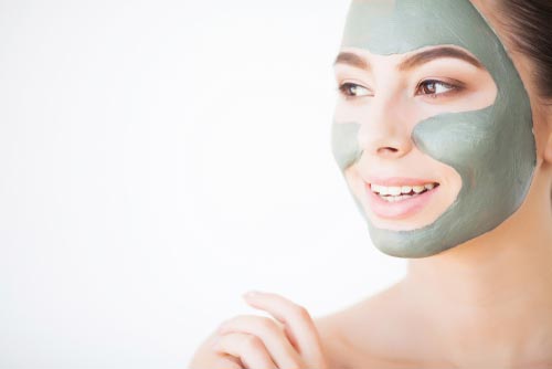 Woman wearing a face clay mask and smiling