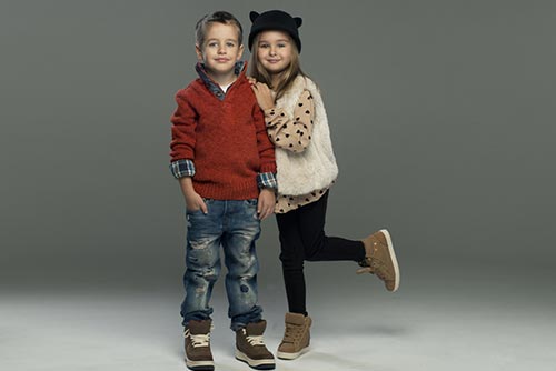 A girl and boy posing wearing tees, cardigan, jeans, and boots