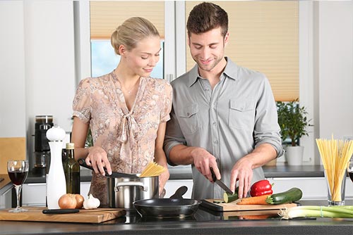 A husband and wife cooking together.