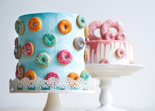 Two doughnut themed-cakes on cake stands