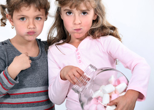 Two girls staring while one holds jar of marshmallows