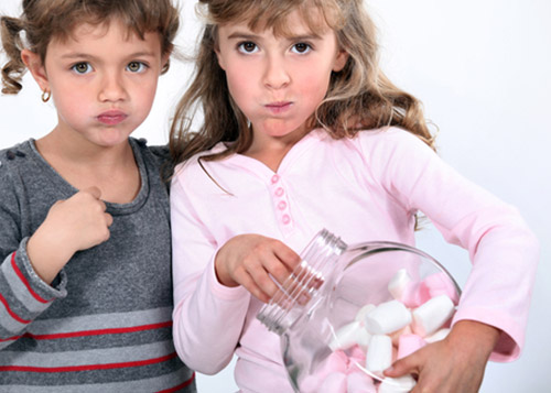 Two girls staring while one holds  jar of marshmallows