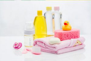 Newborn bathing essentials which include towels, soap, shampoo, brush, and a yellow floating duck