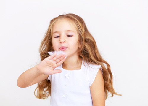 Little girl blowing a feather from the back of her palm