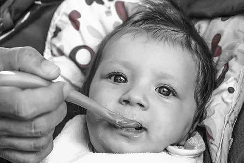 Black and white picture of a baby being fed food