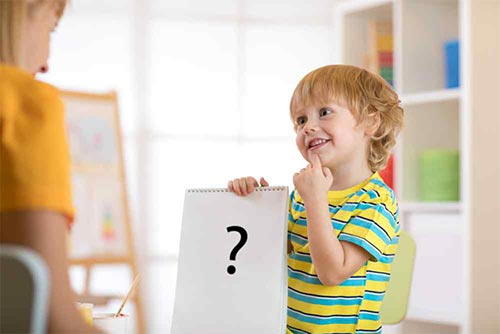Little kid holding up a paper with a question mark and thinking