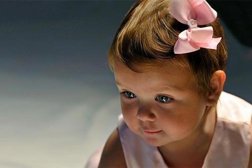 LIttle baby girl staring with a pink bow on her head