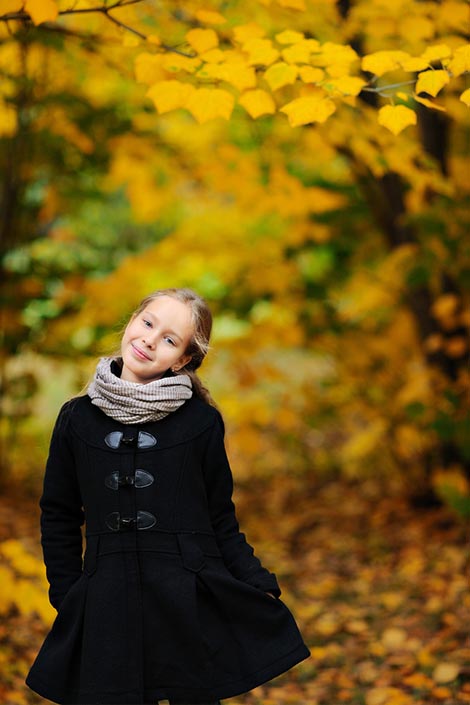 Girl wearing a coat and standing in a park