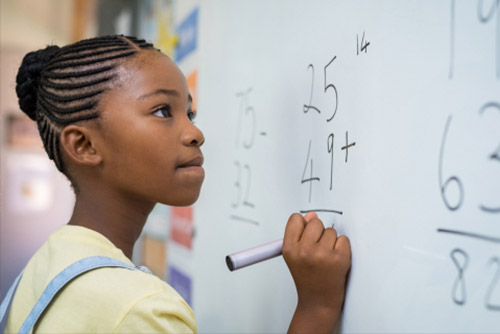 A girl working on a math problem on the whiteboard.