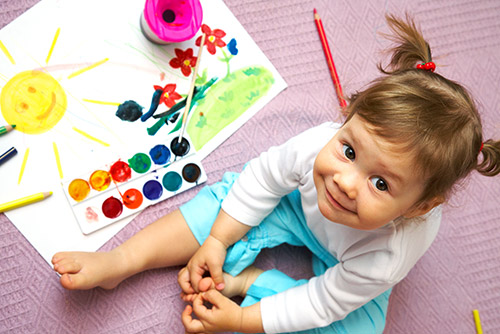 A girl sitting by her art supplies.