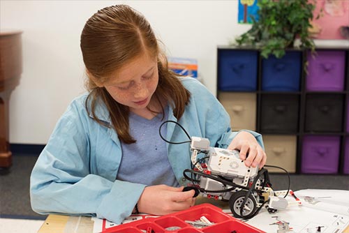 A girl is busy building something out a science kit.