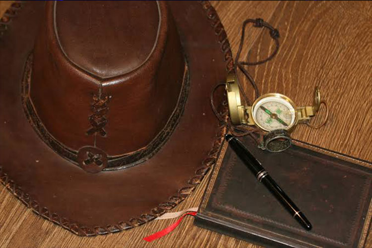 Fedora, pen, journal, compass, and ring