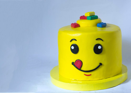 Yellow lego themed-cake with a smiley face