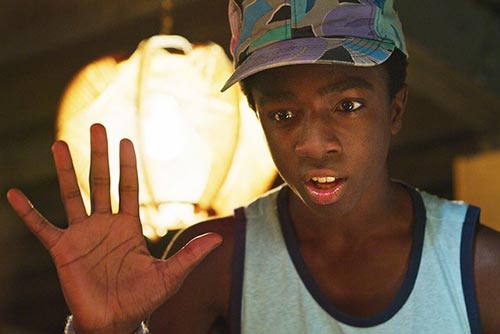 Lucas wearing a sleeveless t-shirt looking confident and raising his palm up.