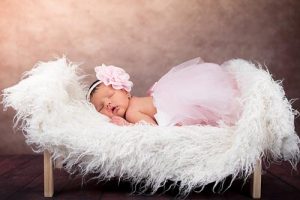 Baby girl sleeping on a chair with a fur cushion