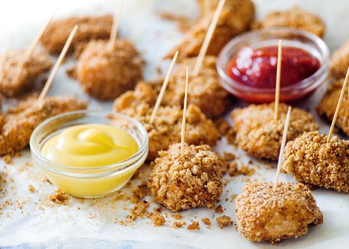 Oat crusted chicken nuggets on skewers with two types of dipping sauce