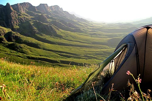 A camping tent surrounded by hills and lush greenery
