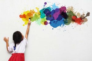 Adorable young girl painting her wall with watercolours