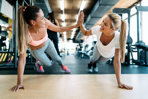Two women doing planks and high-fiving each other