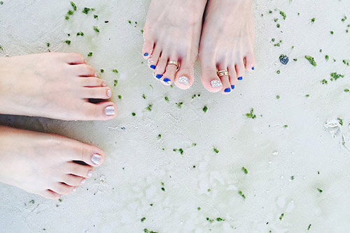 Two pairs of pedicured feet in the water