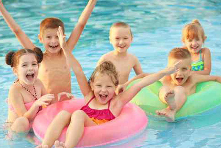 Kids standing in a pool and two kids sitting in swim tubes