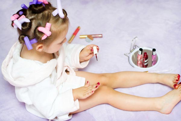Little girl wearing curlers in her hair and applying nail polish