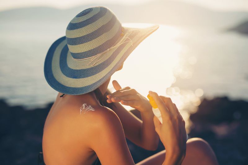 Woman applying sunscreen sitting near the beach
