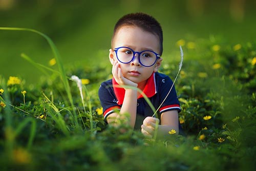 Little boy sitting in the grass and thinking
