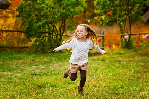 Little girl in tights running through a lawn